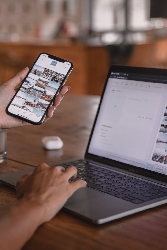 Woman edits social media content on phone and laptop at a cafe in Bali.